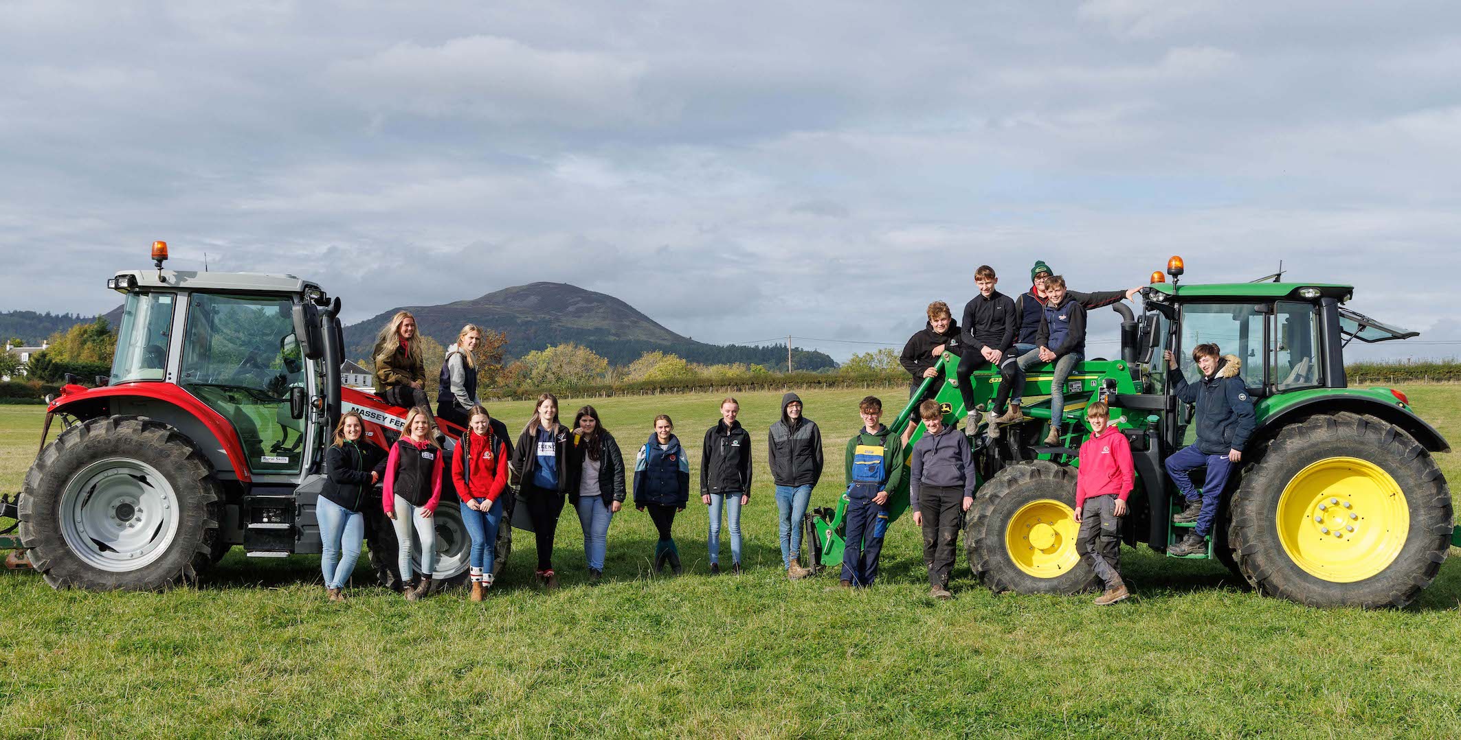 Students standing next to two tractors