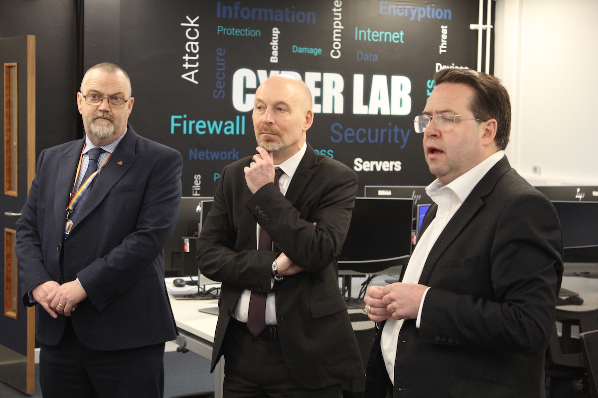 Three people standing in the Cyber Lab classroom at Borders College