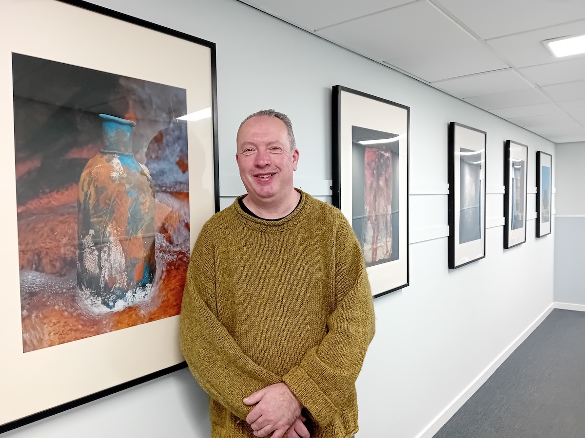 Photo of John Dean standing next to his artwork