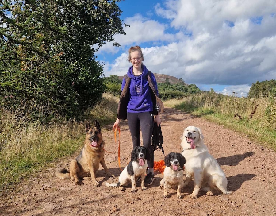 Lucie Shand standing in an outdoor setting alongside four dogs.