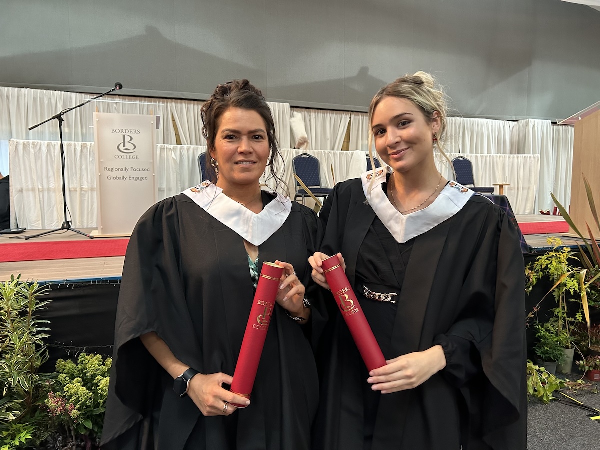 Photo of two graduates holding certificate tubes